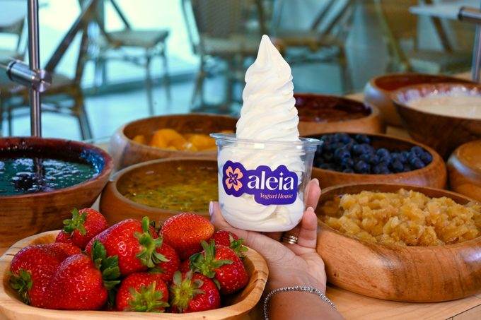 A swirl of aleia Greek frozen yogurt beside a bowl of fresh strawberries