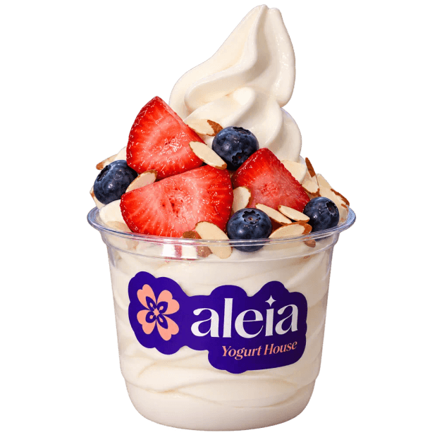 A cup of aleia Greek frozen yogurt topped with strawberries, blueberries, and toasted almonds